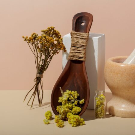 Slika pokazuje eterično ulje u bočici i biljke, tučak i avan korišćene za njegovo pravljenje.