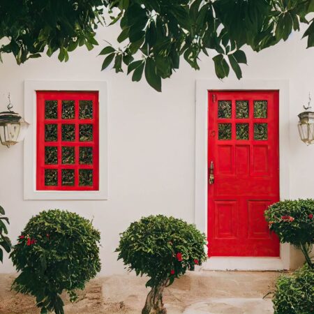 Slika pokazuje kako crvena boja za ulazna vrata unapređuje eksterijer kuće sa belim zidovima.