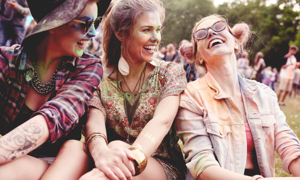 Slika pokazuje tri devojke koje se smeju i uživaju u muzičkom festivalu poput Lovefest 2025.
