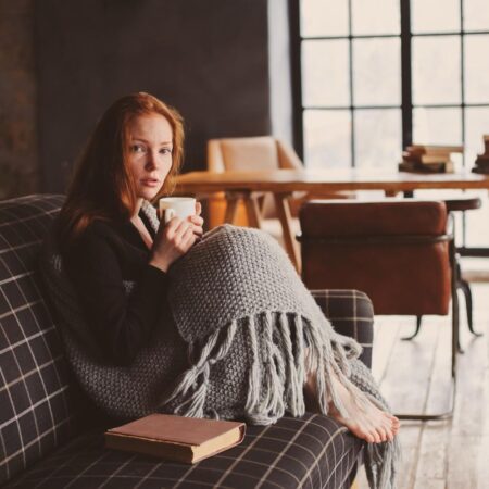 Na slici je žena koja sedi ušukana na kauču spremna da proba razne ideje za hobije.