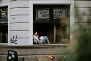Devojka sedi u prozoru kafića i čita jedan neobičan roman.